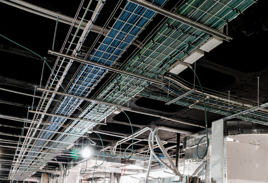 Cable management system with blue and green wires in an industrial setting, showcasing organized wiring infrastructure and network installation.