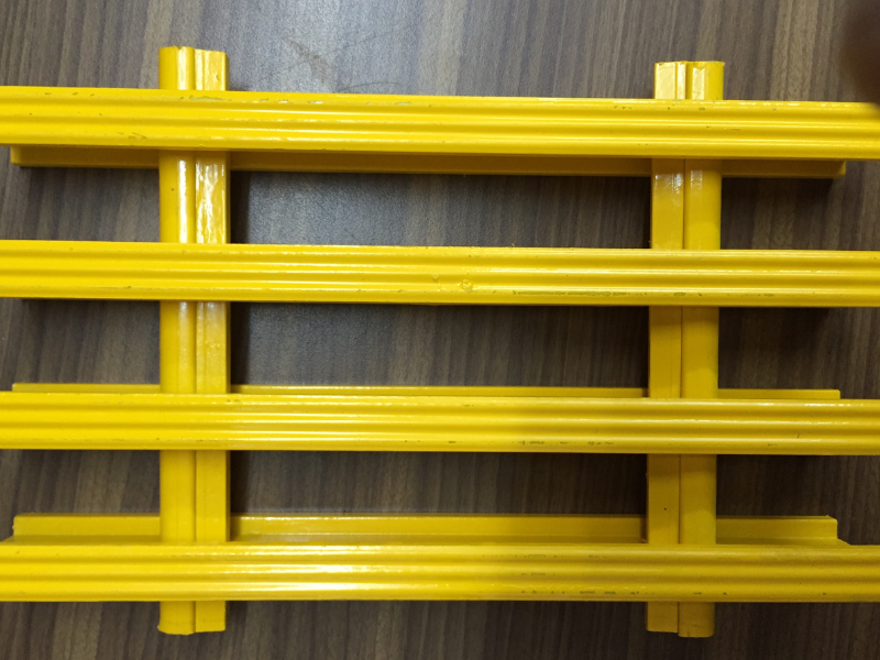 Yellow plastic grid structure on wooden surface, showcasing bright color contrast and industrial design. Ideal for DIY or construction projects.