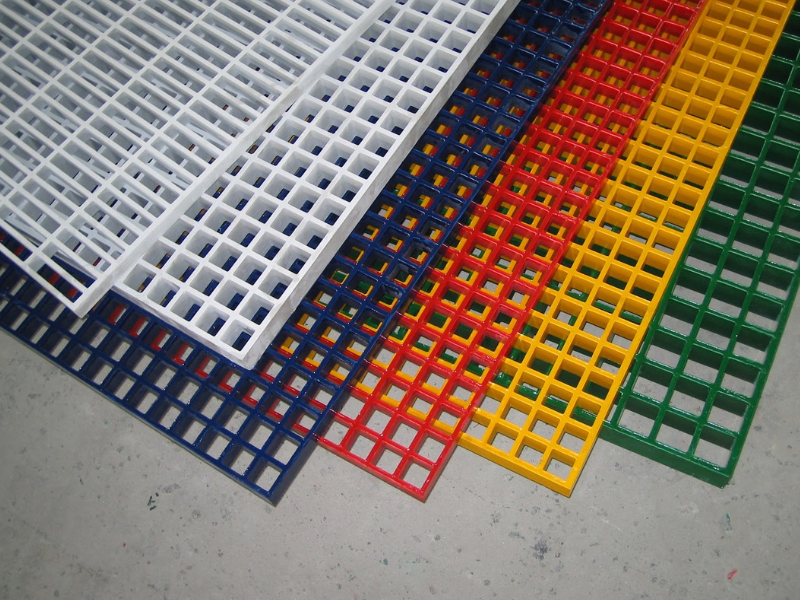 Colorful FRP (fiberglass reinforced plastic) grating panels in white, blue, red, yellow, and green placed on a concrete surface.